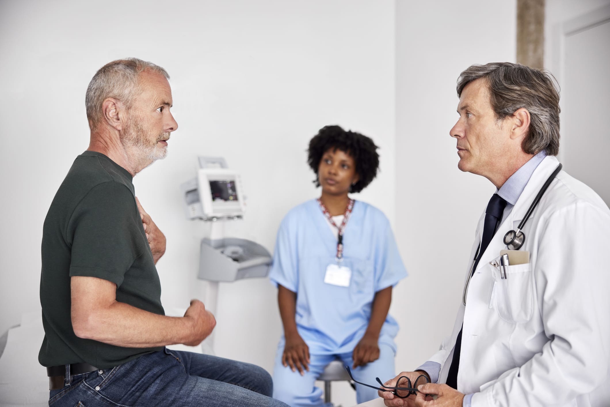 Side view of senior man explaining problems during visit with doctor.