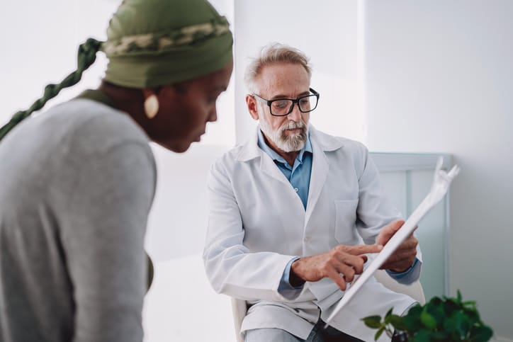 Photo shows an oncologist talking to a patient with cancer/Getty Images