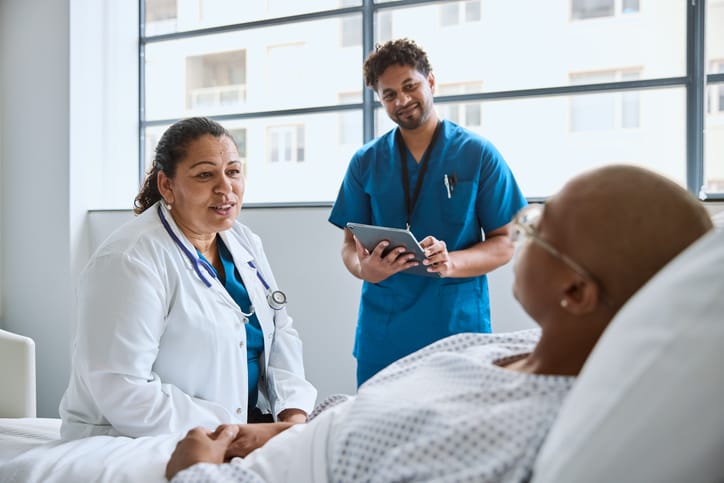 Photo shows a doctor and nurse talking to a patient in a hospital bed/Getty Images