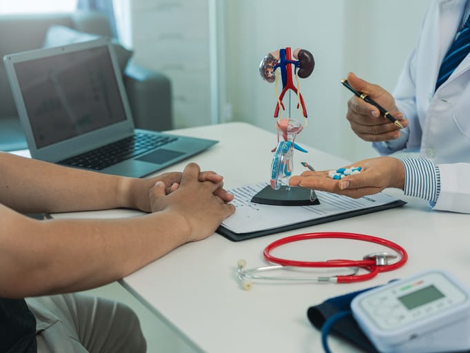 Photo shows a doctor speaking with a patient using a model of the urinary tract/Getty Images