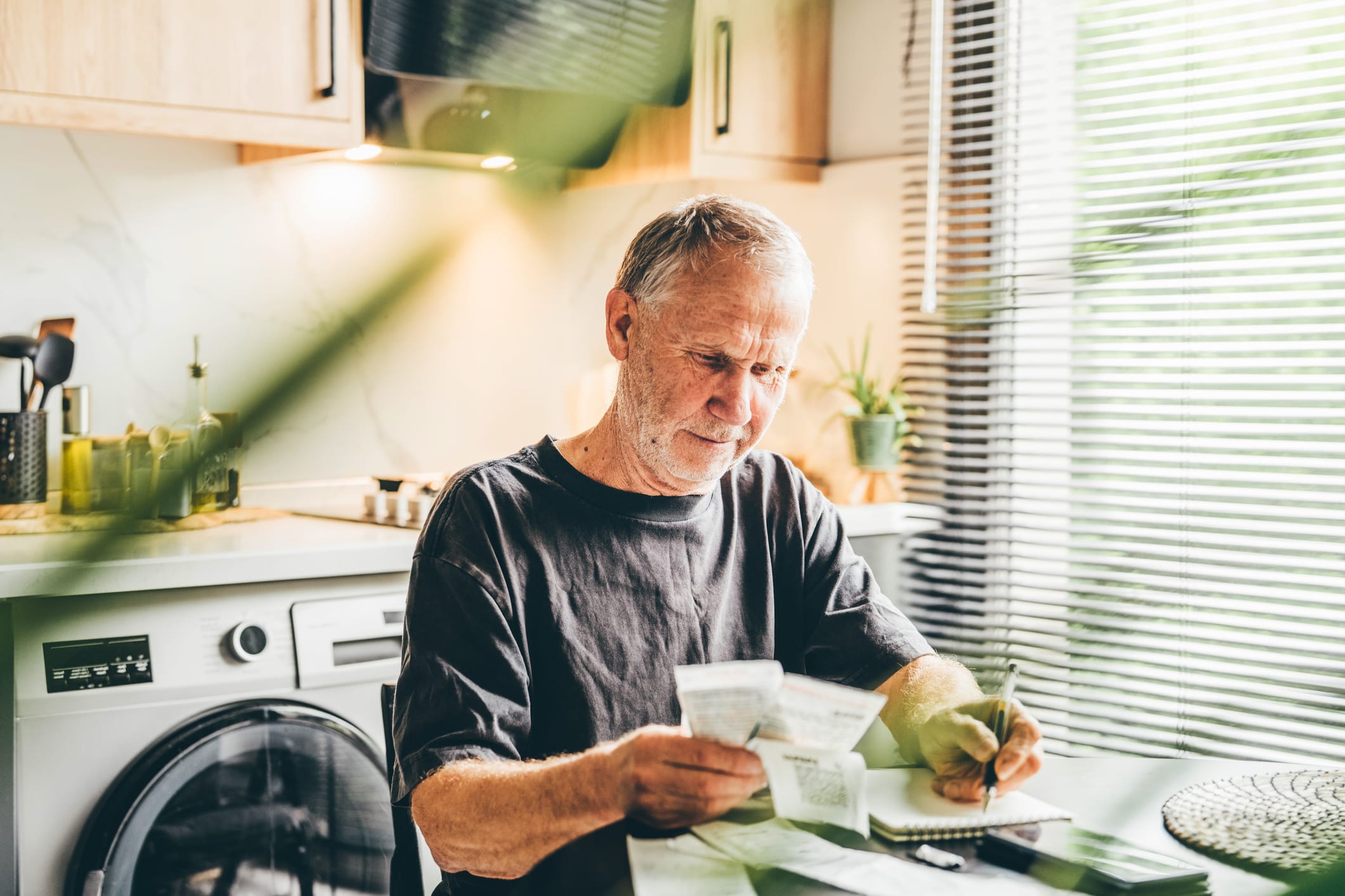 Man seated at kitchen table checking bills