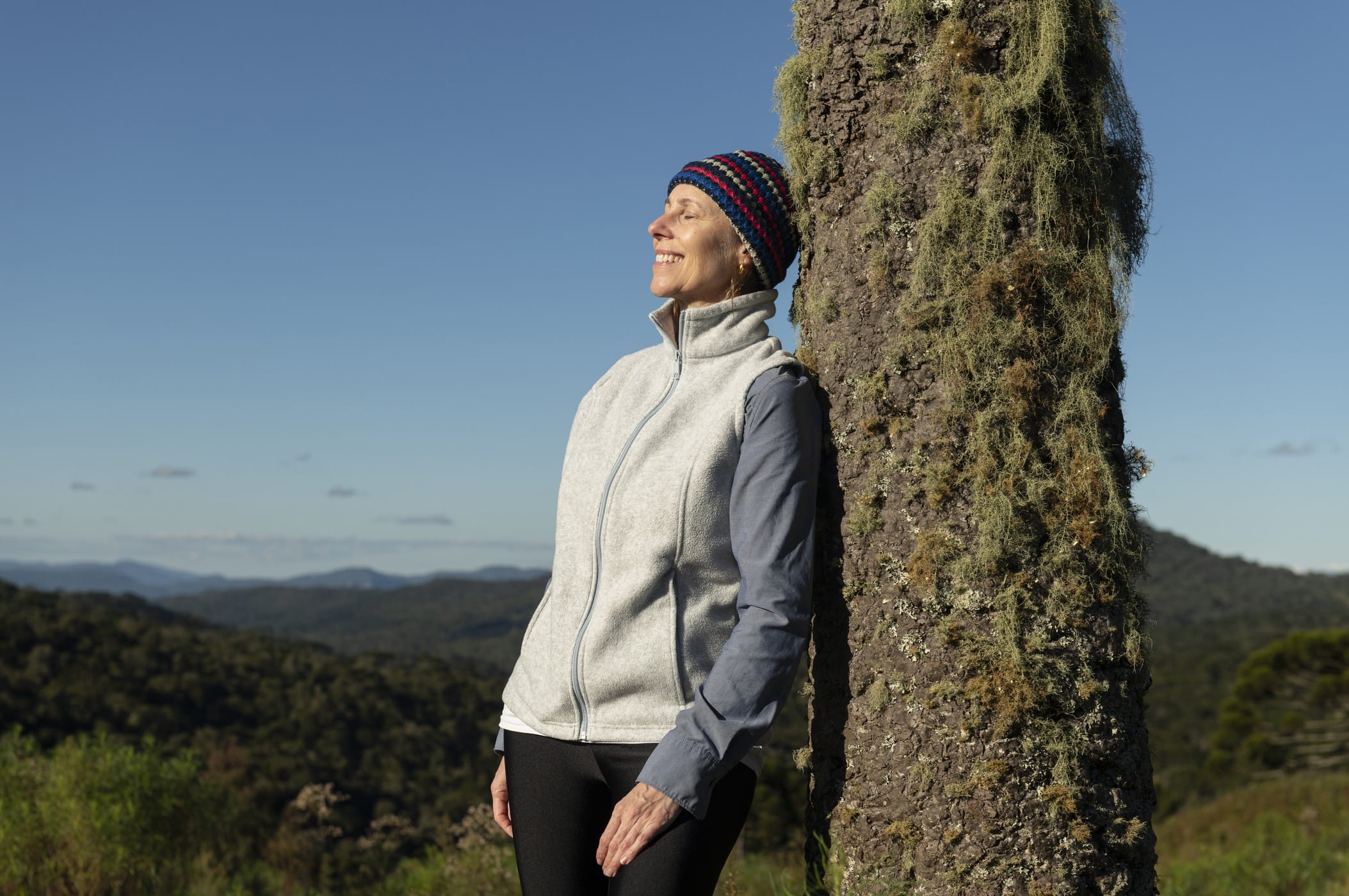 Woman leaning against tree in sun