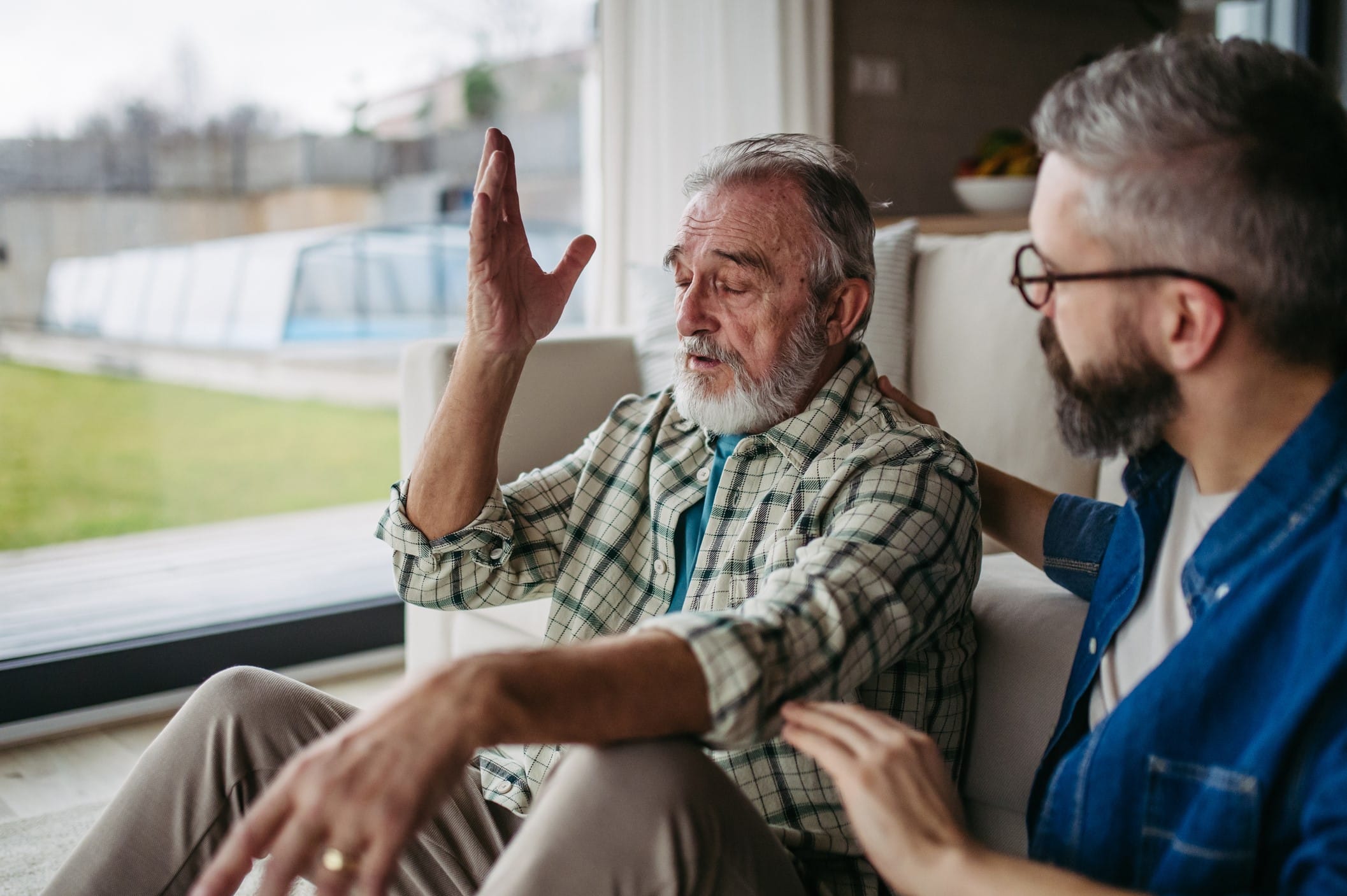 Older man talking to a younger man while both sit on the floor